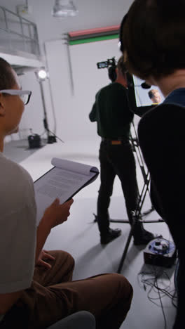 Vertical-Video-Of-Busy-Film-Set-Shooting-Movie-In-Studio-With-Director-Film-Cameraman-Sound-Recordist-And-Assistant-Shot-In-Real-Time